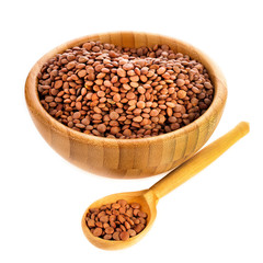 Wooden bowl of brown lentils with spoon isolated on a white background.