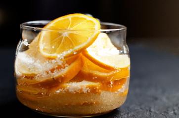  Food black background. Slices of lemon are piled in a glass jar and sprinkled with sugar. Lemon harvesting for tea ceremony.