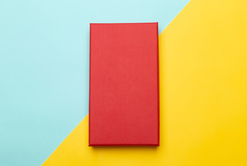 Red box product packaging isolated on yellow half blue background. Flat lay Top view.