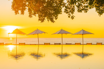 Beautiful tropical outdoor beach sea ocean with umbrella and chiar around outdoor swimming pool at sunset or sunrise time