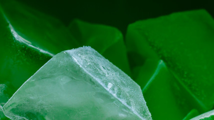 Detailed macro shot of ice cubes on green background 