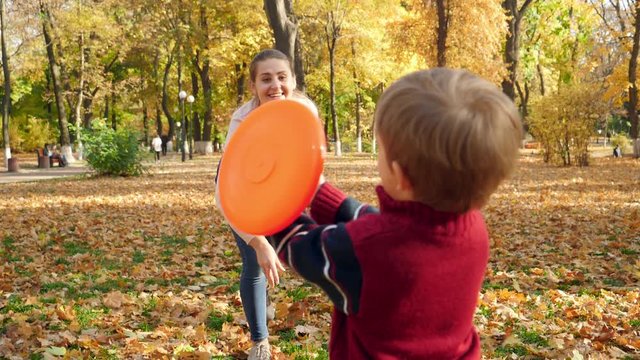 Slow motion video of little boy playing with mother at park and catching frisbee