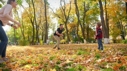 4k video of mother, father and little son playing in park. Family playing frisbee in autumn forest - Powered by Adobe