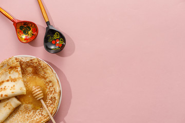 Delicious homemade pancakes with honey on a gently pink background. Top view, close-up. Traditional holiday celebration concept. Russian translation wide and happy Shrovetide Maslenitsa.