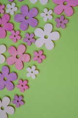 Spring floral decorative background. Purple, pink,  decorative wooden flowers on a green background. Flat style.top view, copy space.Spring season