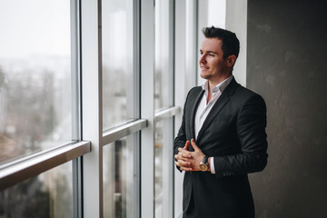 Fototapeta premium Successful and kind businessman looks out of the office window while relaxing