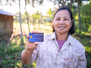 Smiling asian senoir woman showing credit card.