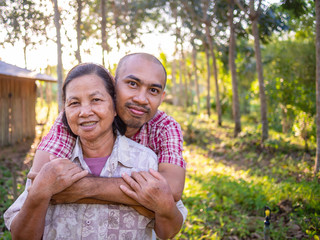 Son hugging mother in rubber plantation.