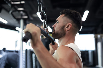 Fit and muscular man shakes his back on the simulator. Back view.