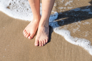 Fototapeta na wymiar Girl's feet in seawater
