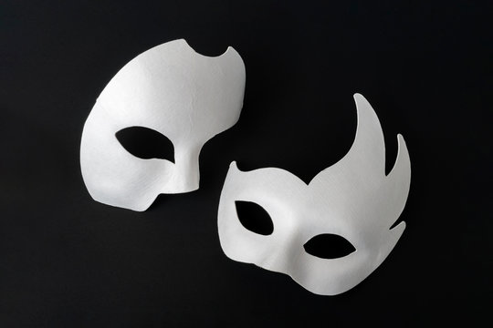 Two white masquerade masks on a black background.