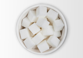 Glass bowl of natural white sugar cubes on white background.
