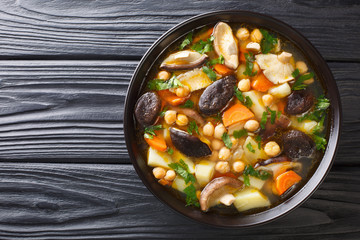 Tasty fresh soup with mushrooms, vegetables and chickpeas close-up in a bowl. Horizontal top view