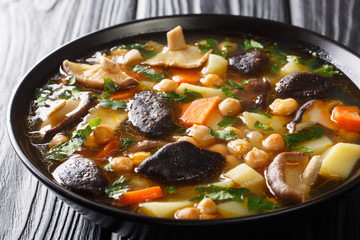 Freshly prepared healthy soup with mushrooms, vegetables and chickpeas closeup in a bowl. horizontal