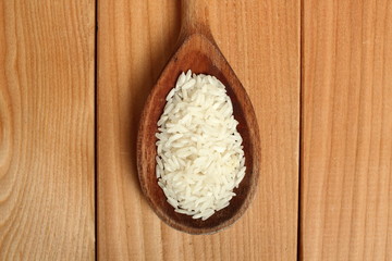 Rice on wooden spoon at plank background. Directly Above.