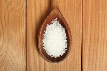 Salt on wooden spoon at plank background. Directly Above.