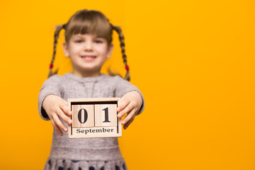Close up portrait of first grader girl with funny pigtails smile looking at camera and hold wooden...