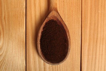 Coffee powder on wooden spoon at plank background. Directly Above.