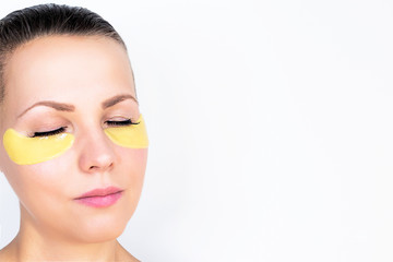 Fototapeta premium pleased Women with Patch Under Eyes, closed her eyes. Young and beautiful female on a white background. Beauty, natural youth, Collagen Mask On Fresh, radiant facial skin. Copy space, close-up