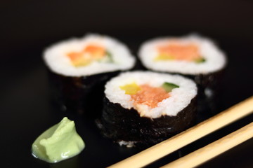 Sushi futomaki with smoked salmon on black plate