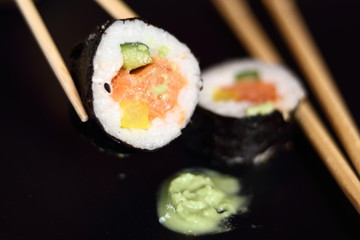 Sushi futomaki with smoked salmon on black plate