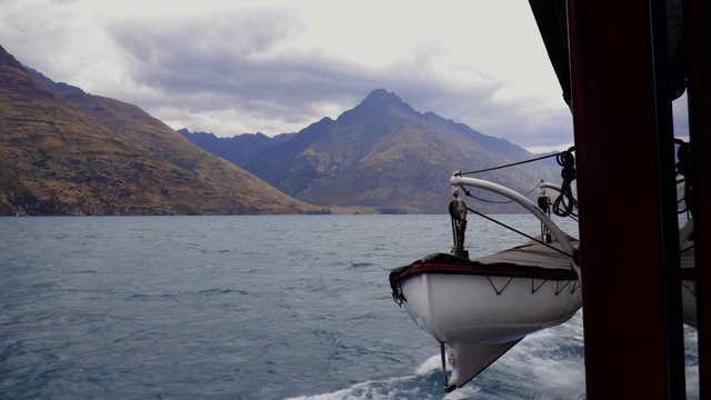 Wide shot of small life boat hanging from TSS Earnslaw with Walters peak in background. Lake, Wakatipu, Queenstown Otago, New Zealand
