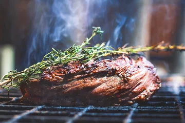 Fotobehang Juicy grilled beef tenderloin, cooked steak meat, food. Barbecue with smoke filet mignon. The meat is cooked, fried over a fire with dark and rosemary. Provencal herbs. Close-up, macro. © Дарья Шуйскова