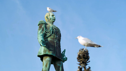 Metal statue of a military commander, green, in Helsinki, close-up with a seagull on his head