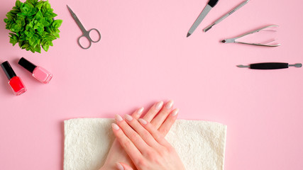 Female hands applying manicure in nail salon.Top view nail studio workspace with manicure tools and...