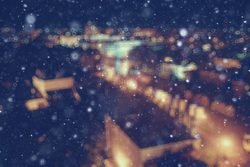 Obraz na płótnie Canvas city lights snow glow background blurred / cityscape blurred bokeh, snowy weather seasonal background winter December