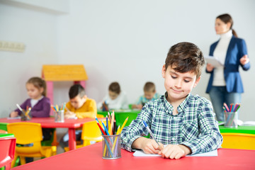Diligent schoolboy writing at lesson