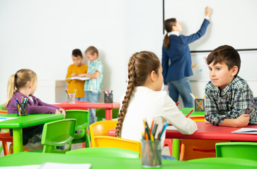 Happy pupils chattering sitting at lesson in elementary school