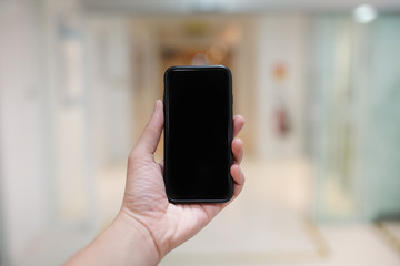 Smartphone with black screen in hand blurred modern office background