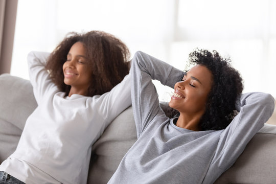 Happy African American Mom And Teen Daughter Relaxing On Sofa