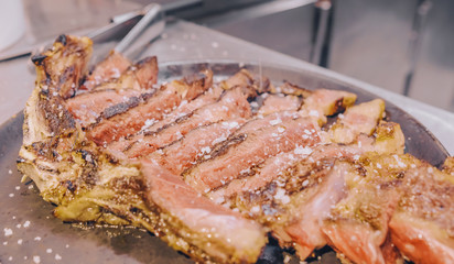 Close up with grilled t-bone steak on a restaurant kitchen plate