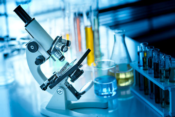 Microscope on the table with chemical tube and glassware in laboratory