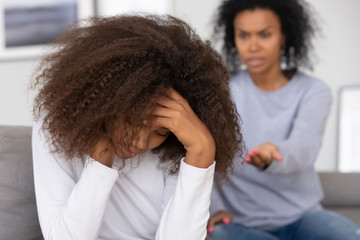 Upset african teenage girl turned back to angry mother scolding