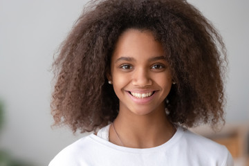Headshot of smiling cute teenage african girl looking at camera