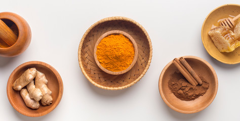 Curcuma powder, cinnamon sticks and honey combs on white