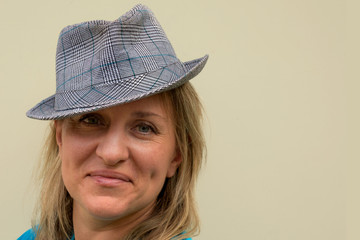 Middle aged woman in hat looks at camera and smiles. Front portrait with positive face