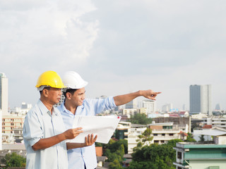 asian male engineer or foreman and architects asian people  wear safety helmet are pointing to...
