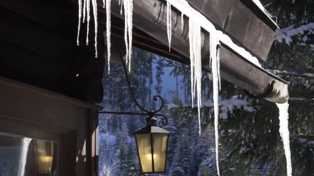 Icicles hanging from a roof in the sunlight.