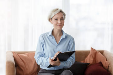 Psychologist Holding Folder Sitting On Sofa In Office