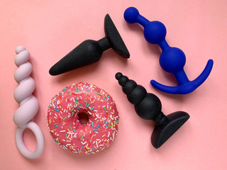 Sex toys. Pink donut and four butt plags on a pink background. Useful for sex shop, adult