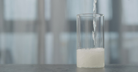 pour transparent drink into glass on concrete countertop