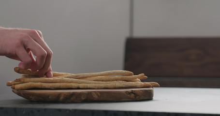 man hand take bunch of homemade grissini from olive board