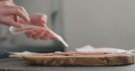 man unpack prosciutto on olive board