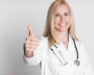 Happy middle-aged woman doctor in uniform with thumb up