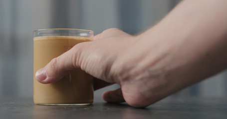 Fototapeta na wymiar man hand take coffee with cream in glass on concrete countertop