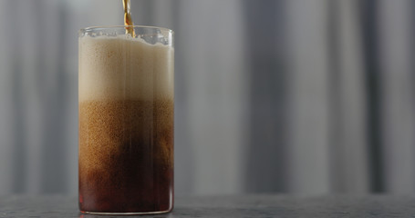 dark beer pour into glass on concrete countertop